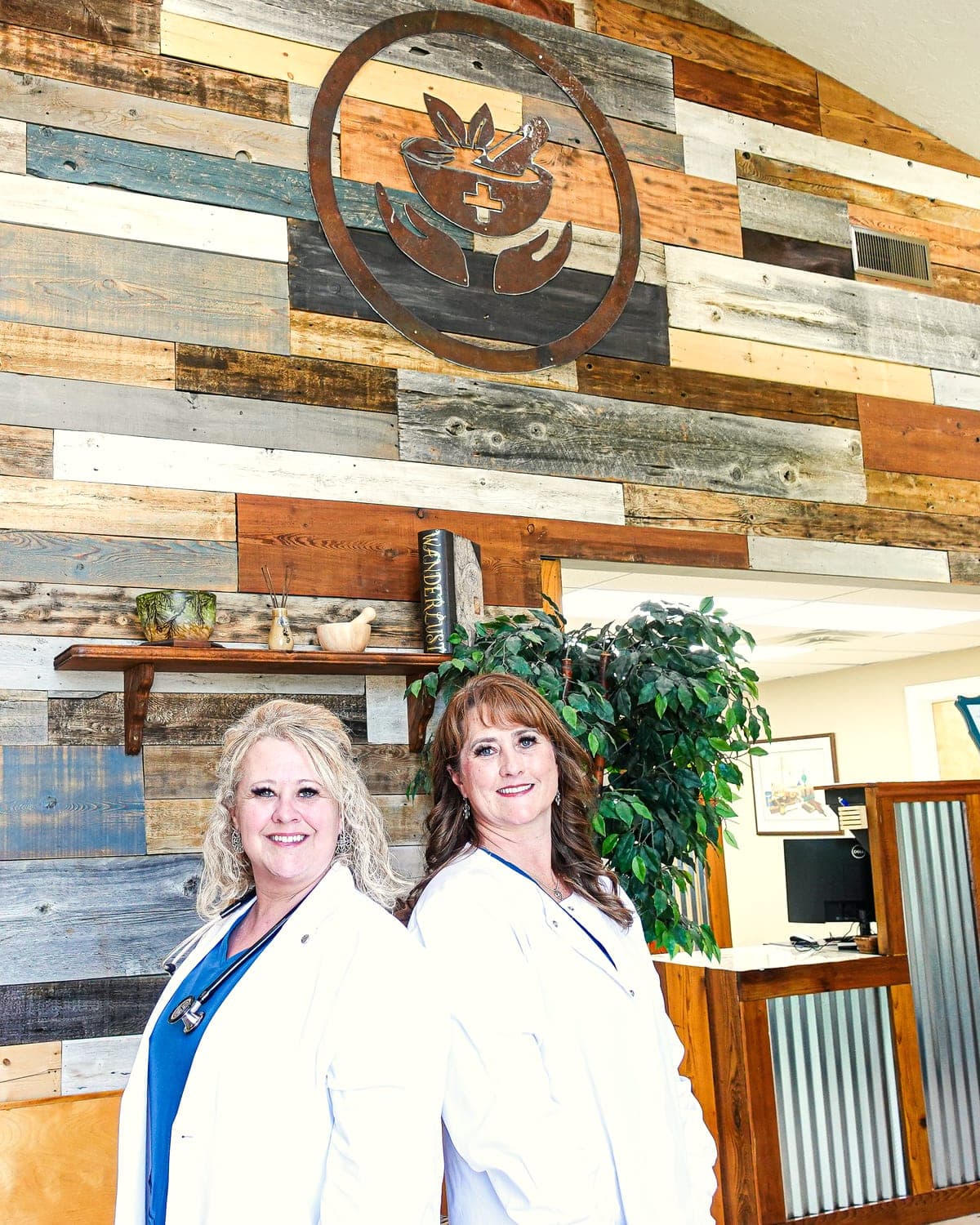 Toni Cantrell and Heidi Winder in the front room of Craft Pharmacy & Clinic, beneath the mortar-and-pestle sign on the reclaimed-wood wall